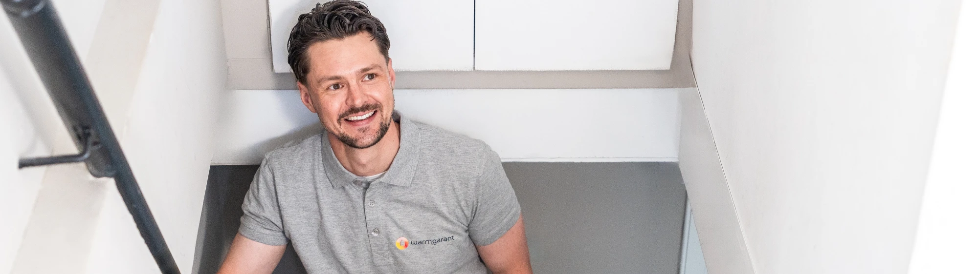 Een installateur van Warmgarant komt de trap van een woning op tijdens een onderhoudsafspraak.