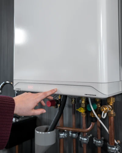 Op de foto zie je een hand die op het display van de een Intergas Xtreme cv-ketel een knop indrukt.