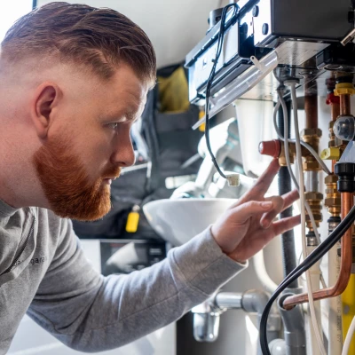 Monteur met rood haar en baard kijkt naar de bedrading van een Intergas cv-ketel.